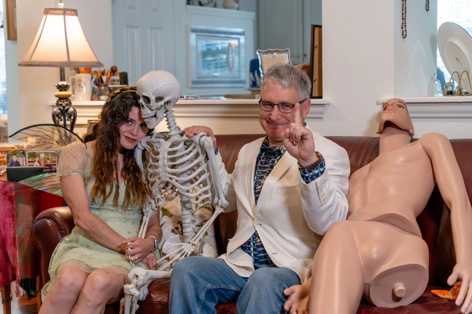 A man in white jacket holding up a skeleton.